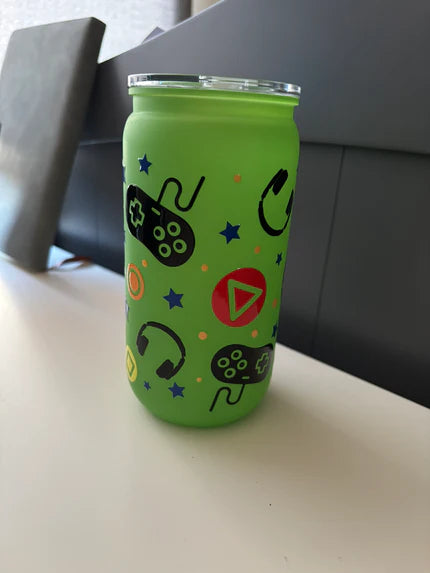 Green tumbler with gaming-themed designs on a white surface