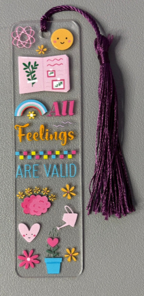 Decorative bookmark with colorful text stating all feelings are valid and illustrations on a gray background