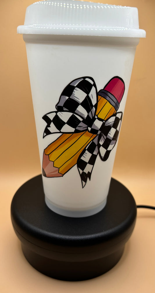 White tumbler with a colorful design of a pencil and checkered bow on a beige background