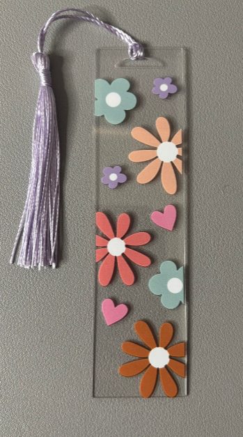 Bookmark with colorful flower designs and a tassel on a gray background