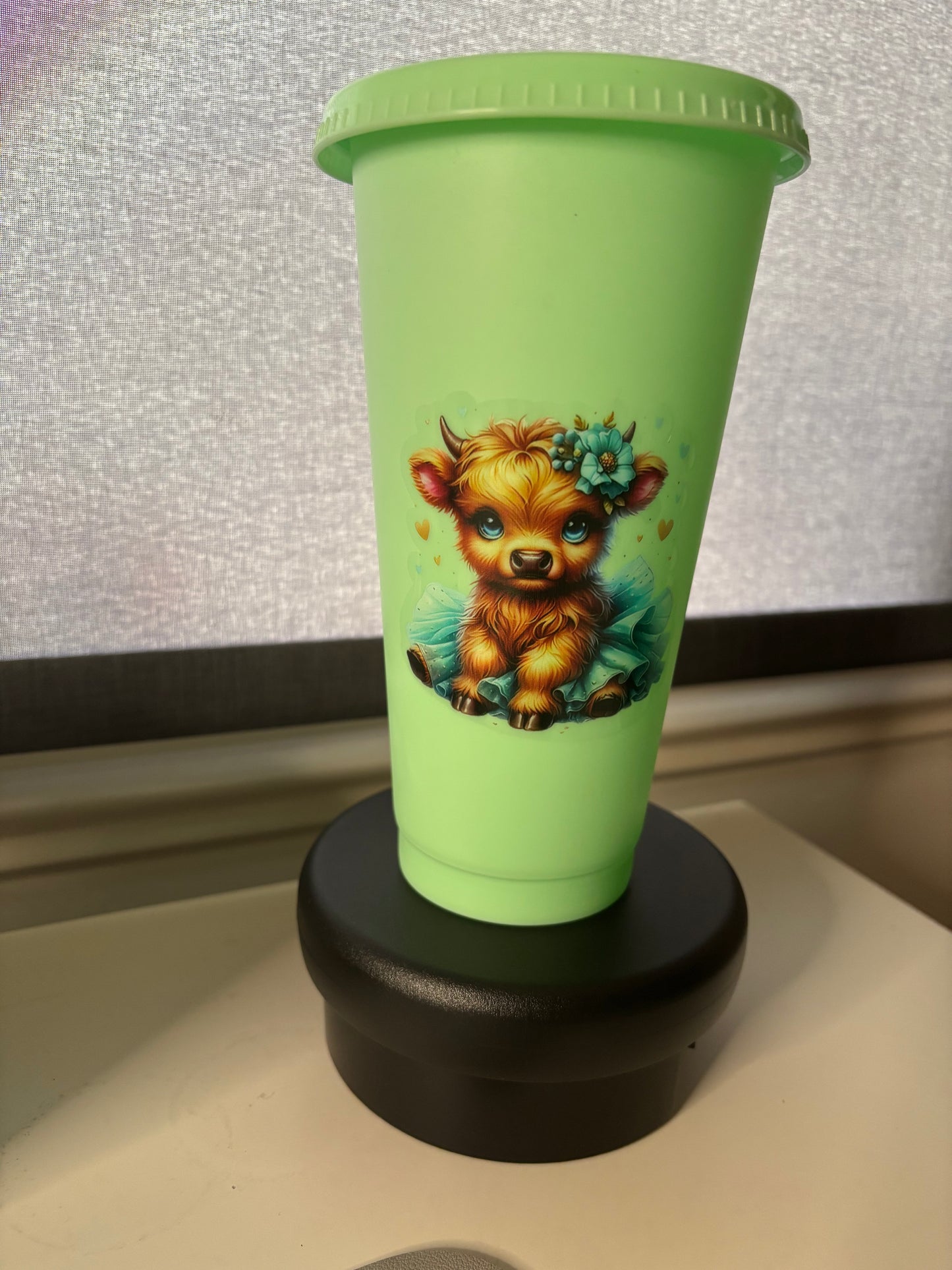 A 24oz green cold cup tumbler with a Highland Cow decal, a straw lid, and a matching straw.