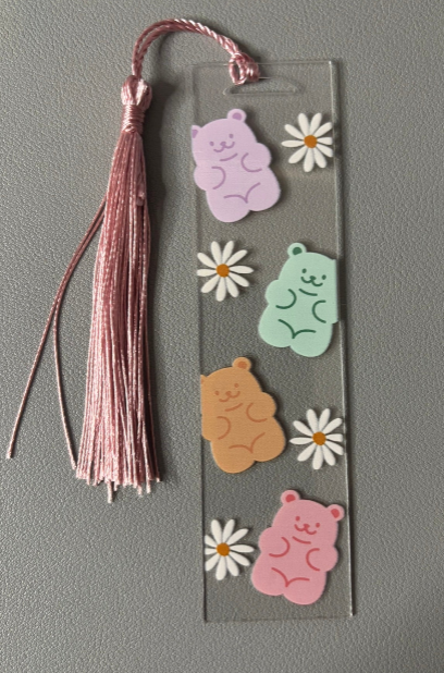 Bookmark with colorful bear-shaped stickers and a tassel on a gray background