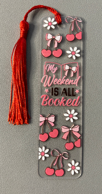 Decorative bookmark with tassel, flowers, hearts, and text saying my weekend is all booked  on a gray background
