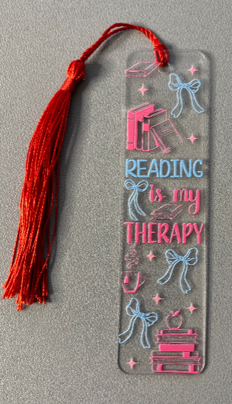 Decorative bookmark with 'Reading is my Therapy' text and tassel on a gray background