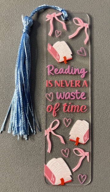 Decorative bookmark with tassel and 'Reading is never a waste of time' text on a gray background