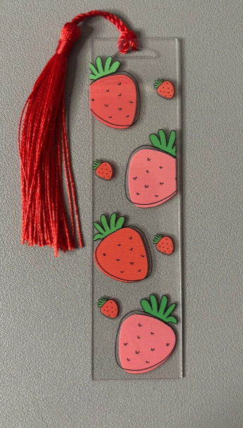 Bookmark with strawberry designs and a red tassel on a gray background