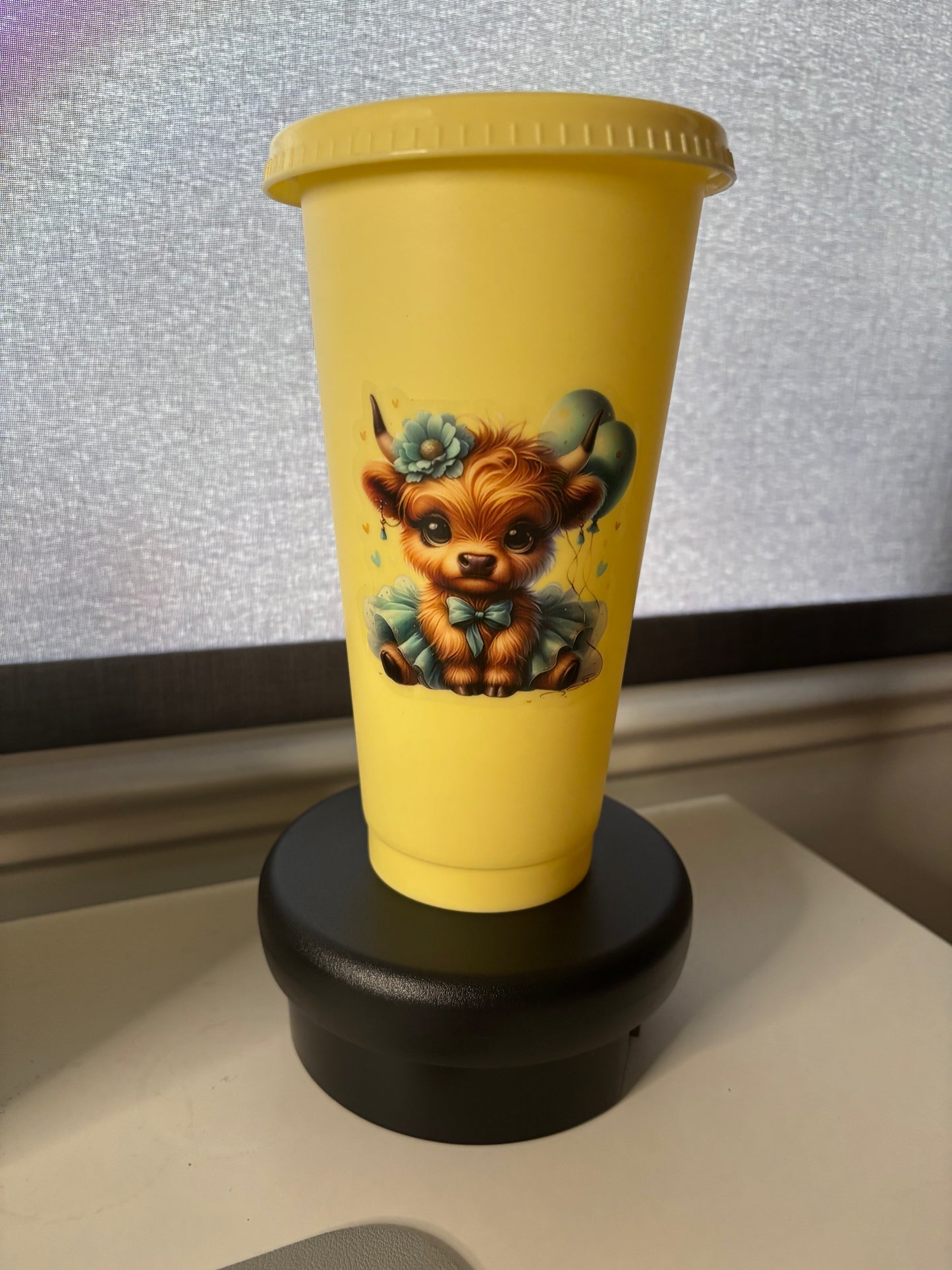 A 24oz yellow cold cup tumbler with a Highland Cow decal, a straw lid, and a matching straw.